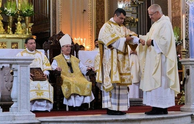 Auxiliary Bishop Luis R. Zarama, seated center, looks on as Rev. Mr. Gerardo Ceballos is vested by Msgr. Al Jowdy, pastor of Immaculate Heart of Mary Church in Atlanta. Bishop Zarama ordained Rev. Mr. Ceballos to the transitional diaconate May 23 at the Metropolitan Cathedral in Morelia, Mexico. 