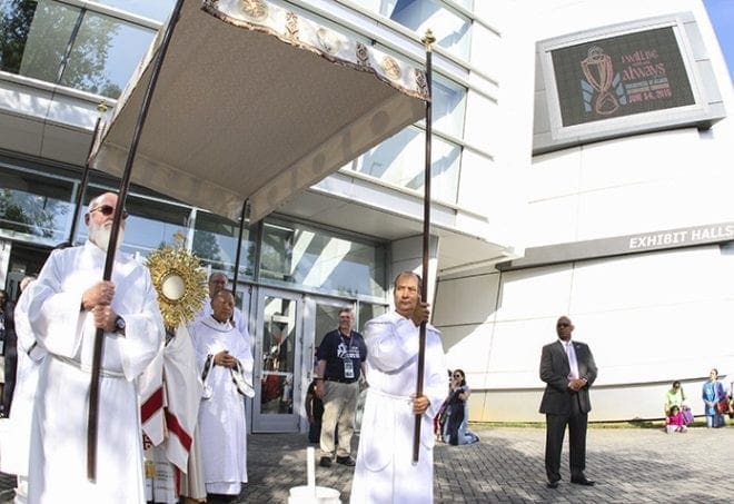 Archbishop Wilton D. Gregory prepares to carry the monstrance holding the Real Presence of Jesus in the Eucharist to the main exhibit hall of the Georgia International Convention Center, College Park, during the morning procession June 6. Photo By Michael Alexander 