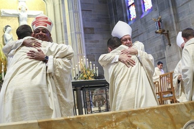 (Facing the camera, l-r) Archbishop Wilton D. Gregory, Bishop Luis Zarama and Bishop David Talley are the first to offer a sign of peace and welcome to Father Brian Bufford, Father Jorge Carranza and Father Branson Hipp, respectively. Photo By Michael Alexander