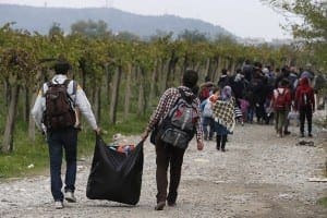 Refugees carry their belongings in Macedonia after crossing from a transit camp in Idomeni, Greece, Oct. 19. Refugees were walking to reach a train station to go to Belgrade, Serbia. Thousands of refugees are arriving into Greece from Syria, Afghanistan, Iraq and other countries and then traveling further into Europe. 