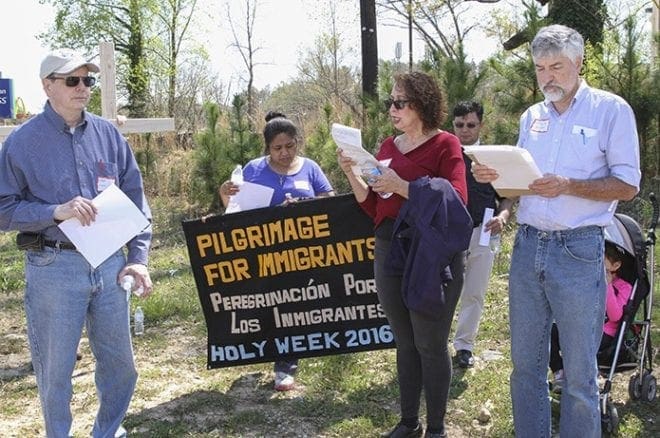 (Foreground, l-r) Immaculate Heart of Mary parishioners Kent Williams, Clara Azcunes and Mark Bracken and the rest of the marchers stop three blocks west of Interstate 85 and pray before proceeding to the church. In the background are Guadalupe Robles and Father Fabio Sotelo of St. Bede’s Episcopal Church, Atlanta. Photo By Michael Alexander