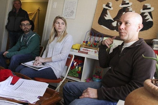 Sitting among a group of people in the El Refugio living room, co-founder PJ Edwards, right, conducts an orientation regarding what to expect when they visit some detained men inside Stewart Detention Center in Lumpkin. Photo By Michael Alexander