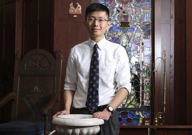 Holy Spirit Preparatory senior Tom Yao stands before the baptismal font in the school’s St. Joseph Oratory, where he converted to Catholicism last year. Photo By Michael Alexander