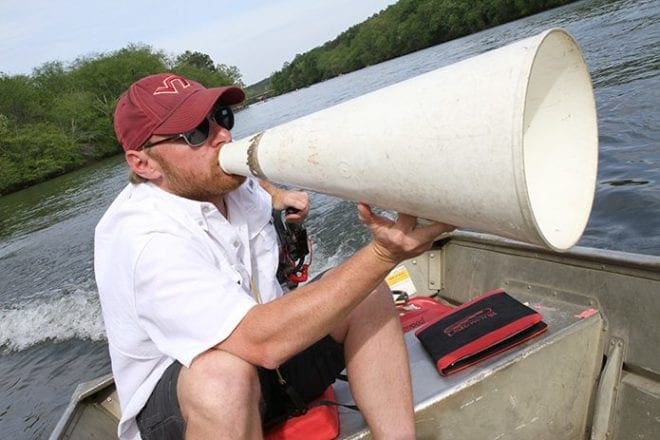 Varsity men’s coach Nick Johnson, an alumnus of Virginia Tech, shouts out commands to rowers from the stern of the coach launch boat. Johnson, a native of Alexandria, Va., is in his first season of coaching at the St. Andrew Rowing Club. Photo By Michael Alexander